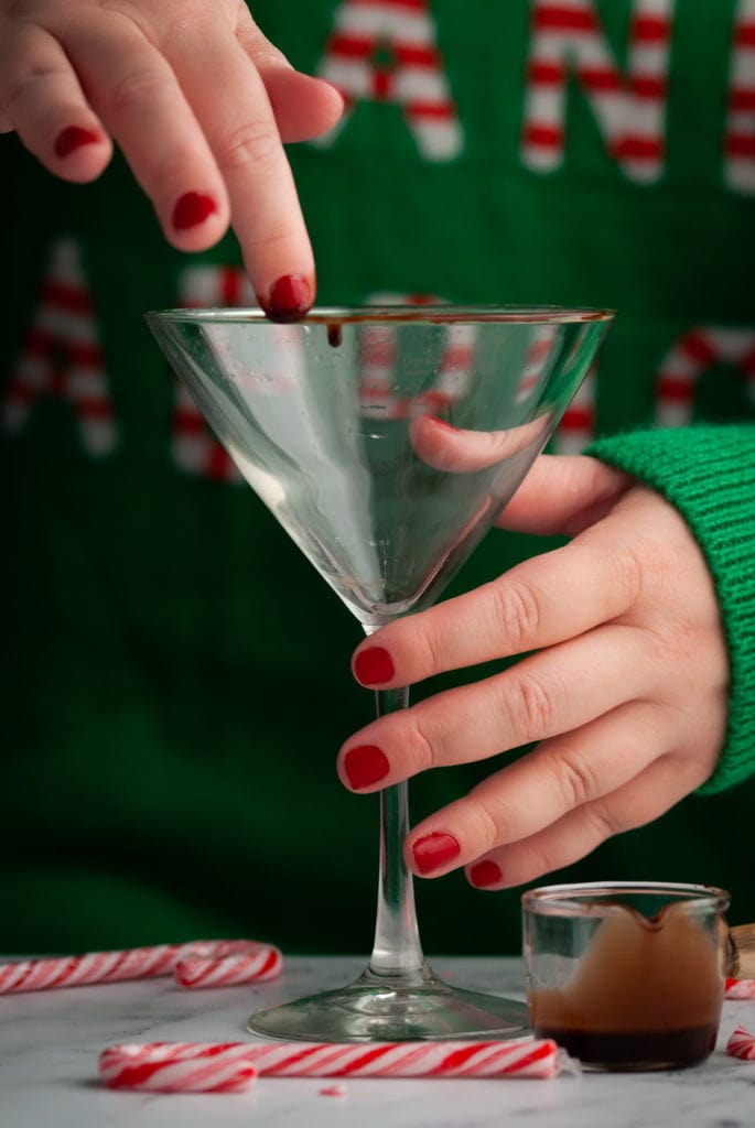 using finger to wet rim of martini glass with chocolate syrup