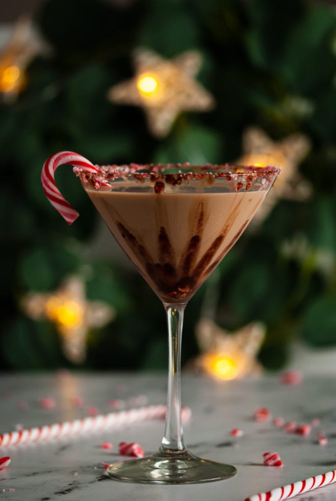 peppermint mocha martini in front of christmas decor incliuding greenery and star lights