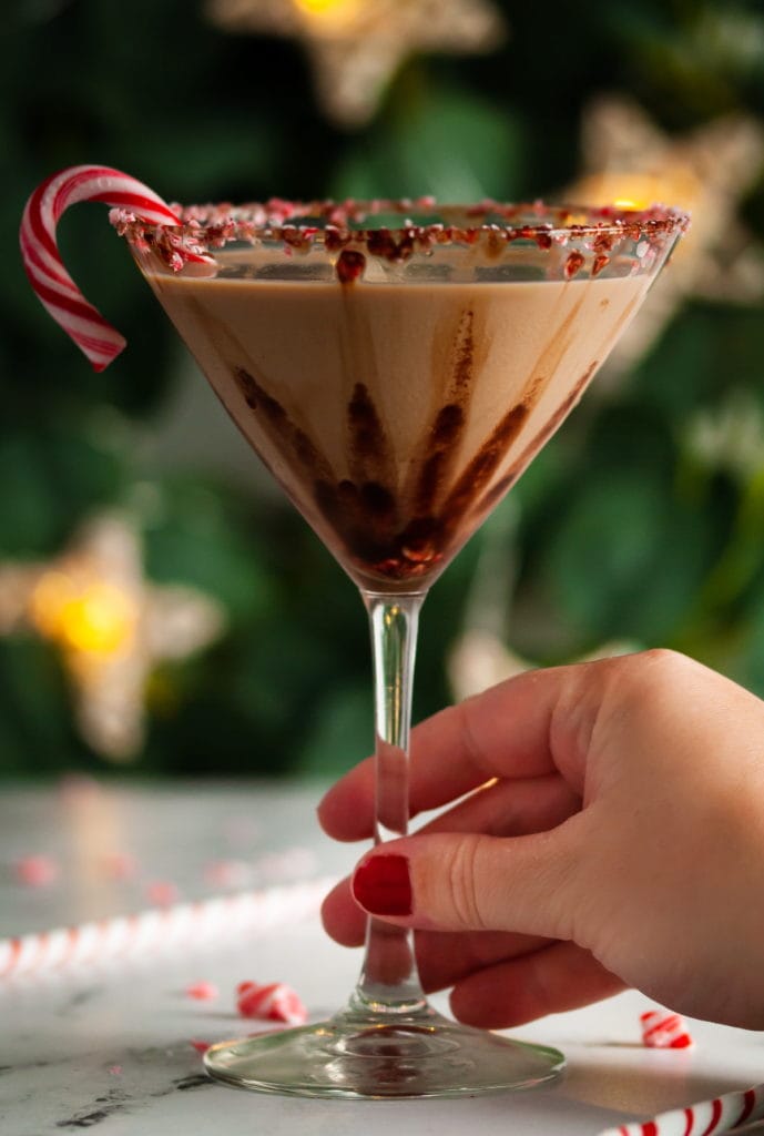 Hand reaching in to grab a Christmas themed martini