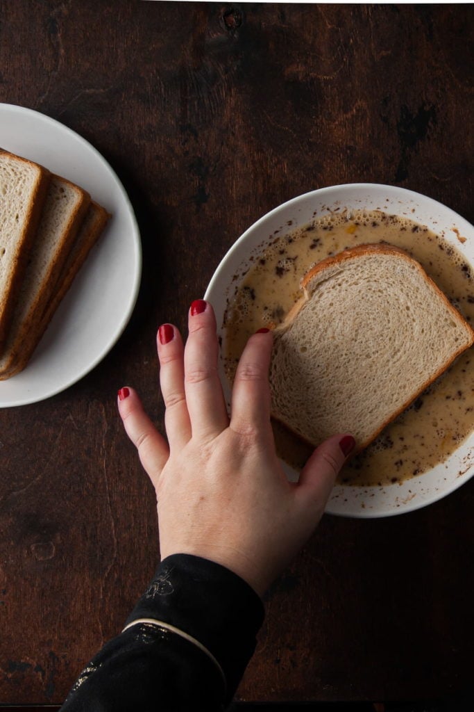 dipping sourdough bread into seasoned egg wash