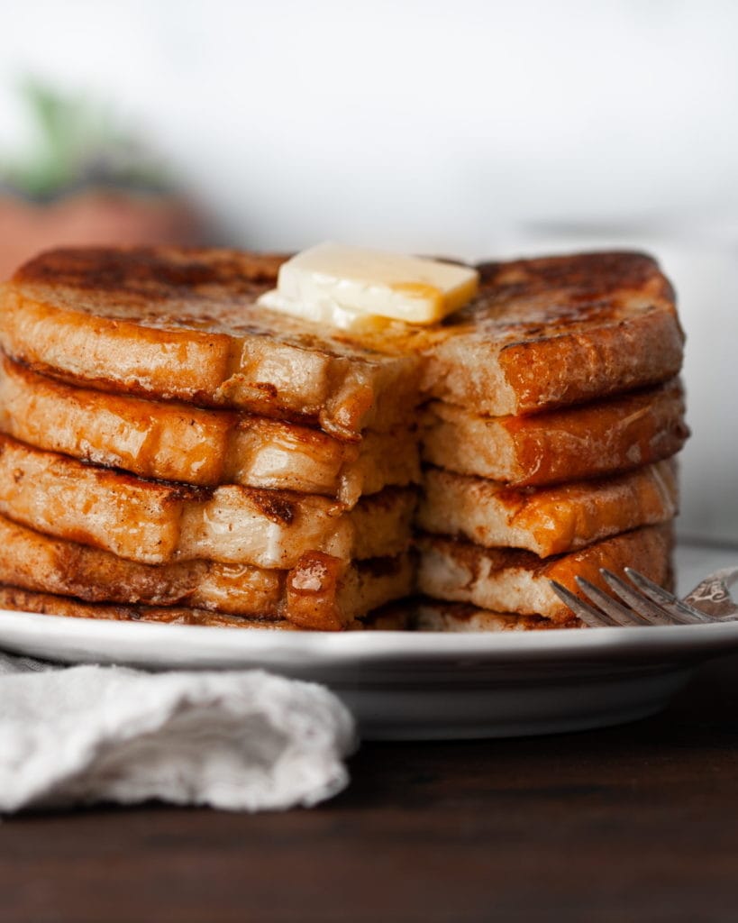 close up iof stack of french toast with bite taken out 