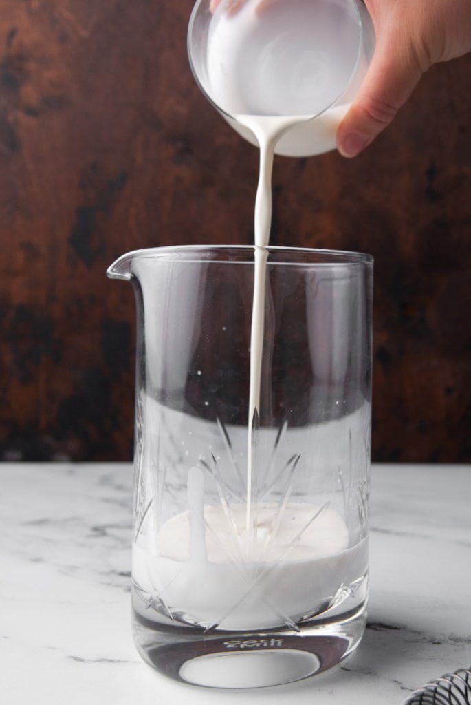 pouring white chocolate liqueur to a cocktail mixing glass
