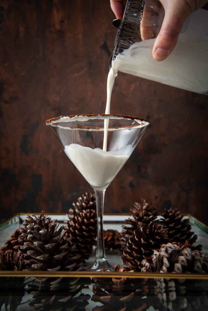 Pouring white chocolate martini into garnished martini glass.