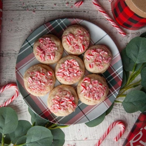 green and red plaid plate with 7 candy cane shortbread cookies and surrounded by candy canes and eucalyptus