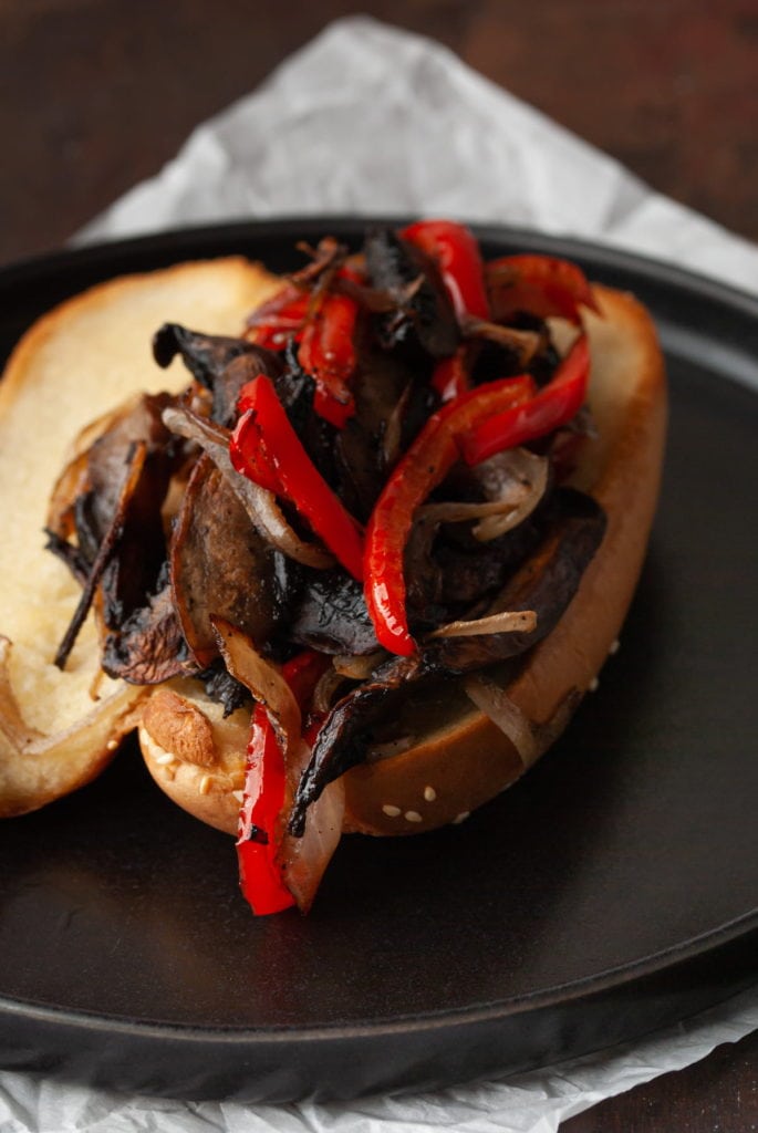assembling marinated portobello mushrooms, red pepper, and onions on a toasted hoagie roll