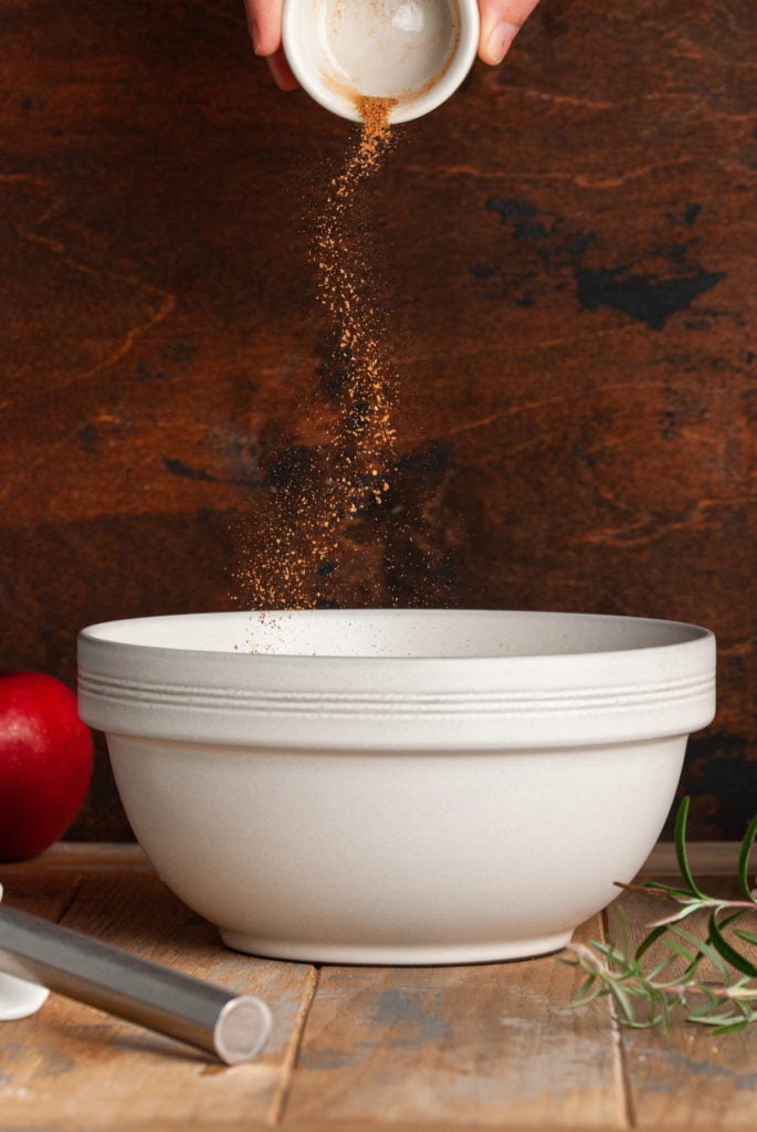 adding nutmeg to a large mixing bowl