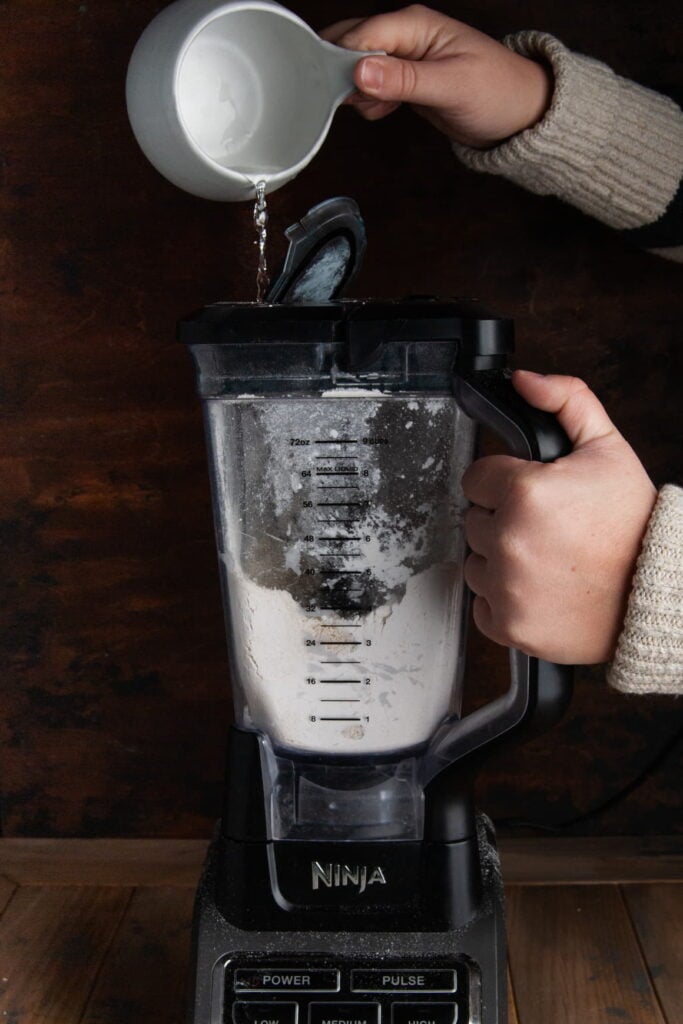 Adding cold water to a blender while it is on to form a quiche crust.