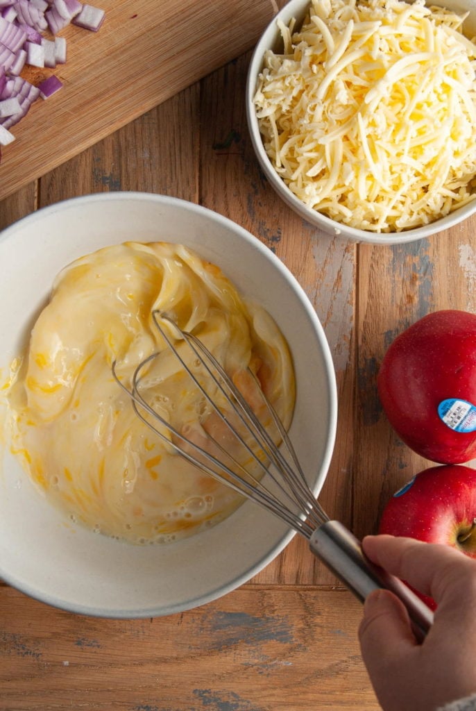 vigorously whisking eggs and milk to get a smooth filling for a quiche