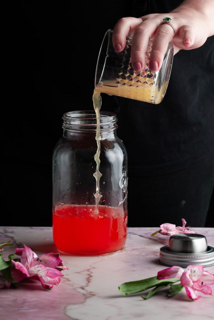 adding pineapple juice to a cocktail shaker