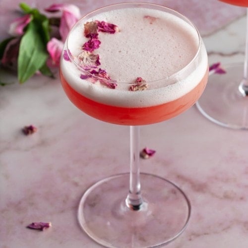 Love Potion Cocktail surrounded by flowers and garnished with rose petals