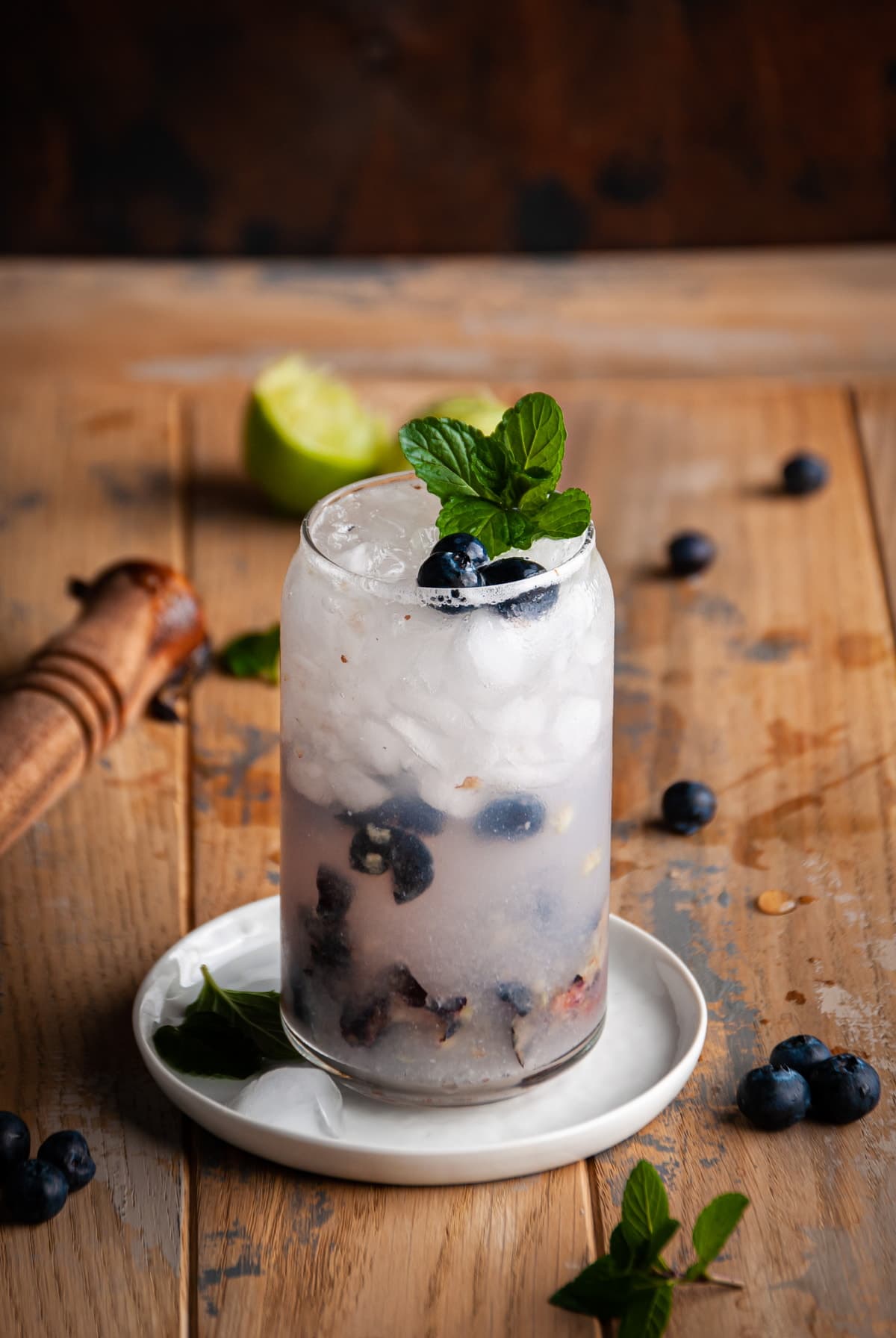blueberry gin fizz on a wooden table and garnished with blueberries and mint