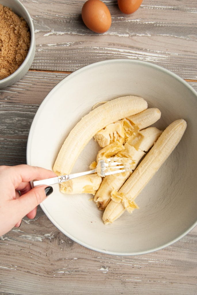 crushing bananas with a fork to make banana bread