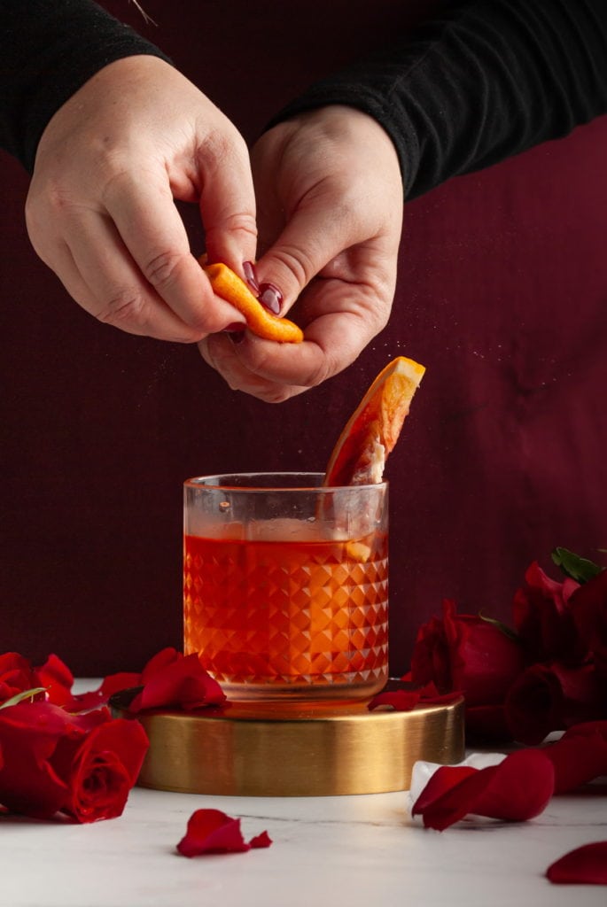 Squeezing orange peel over Negroni