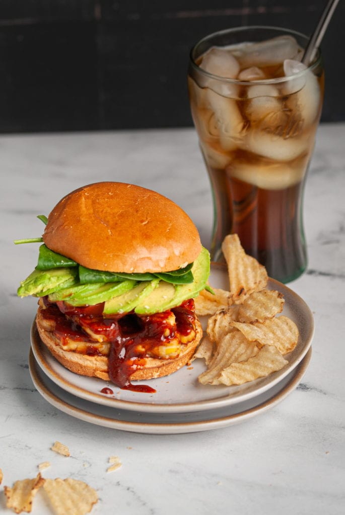 vegan bbq sandwich with chips and a coca cola