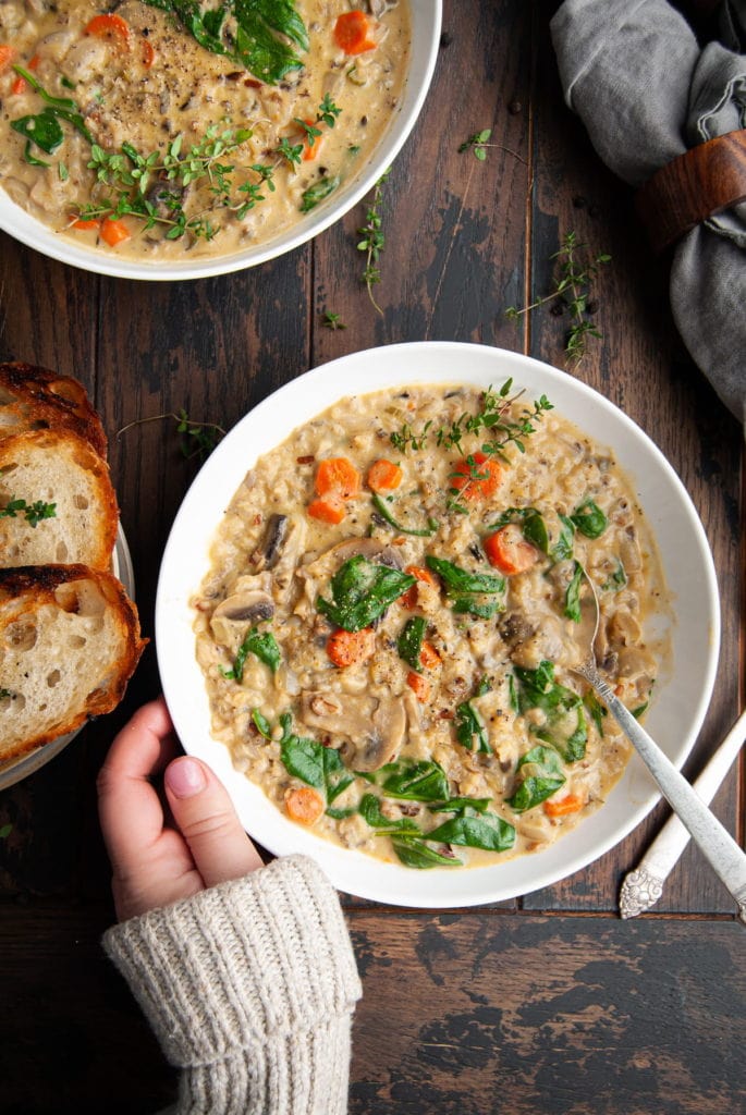 two bowls of creamy soup with hand cupping the lower bowl