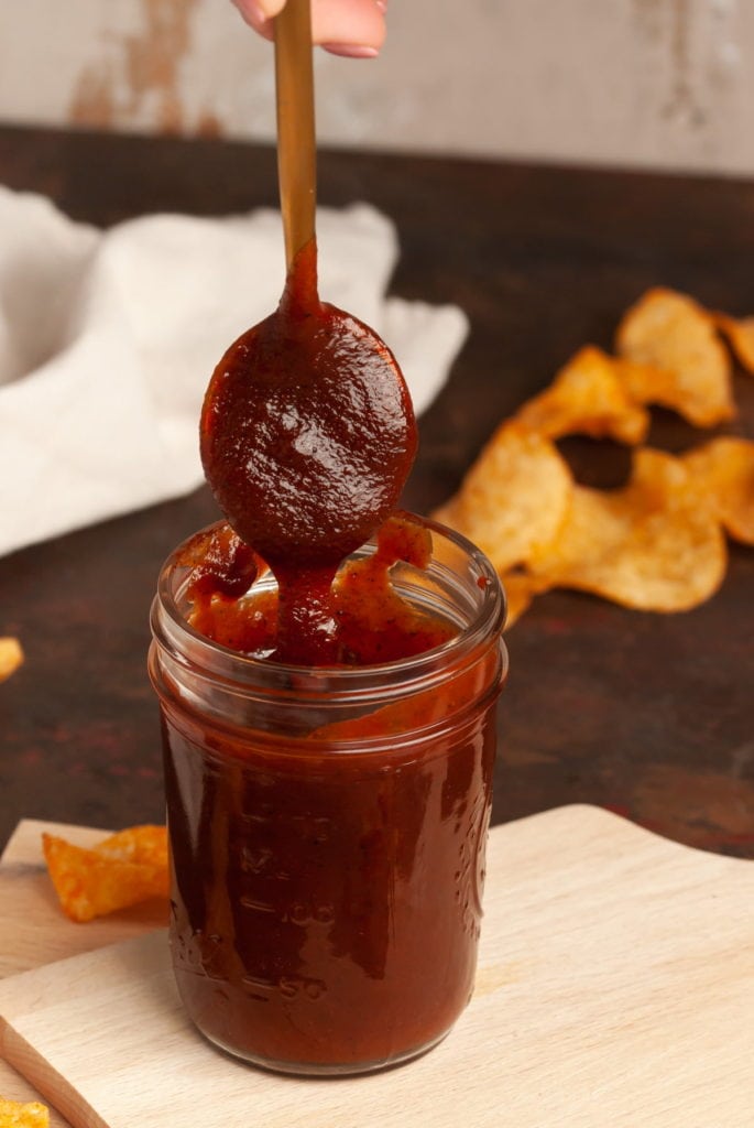 bbq sauce dripping off a spoon into a jar