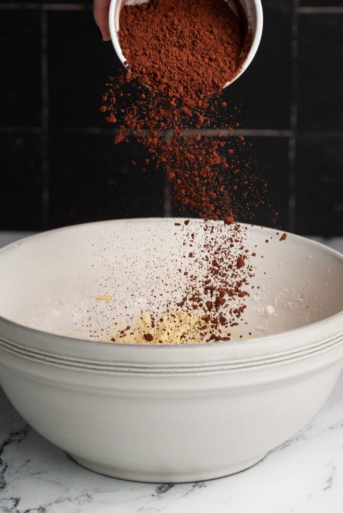 Adding cocoa powder to one half of brownie batter.