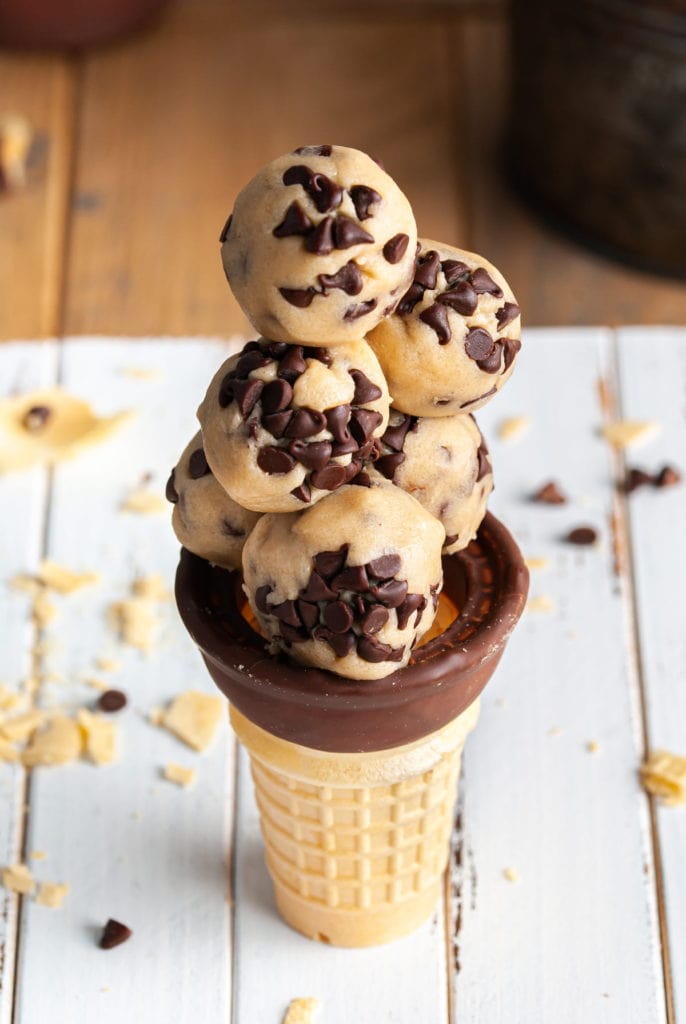 a stack of cookie dough bites in an ice cream cone on a white board