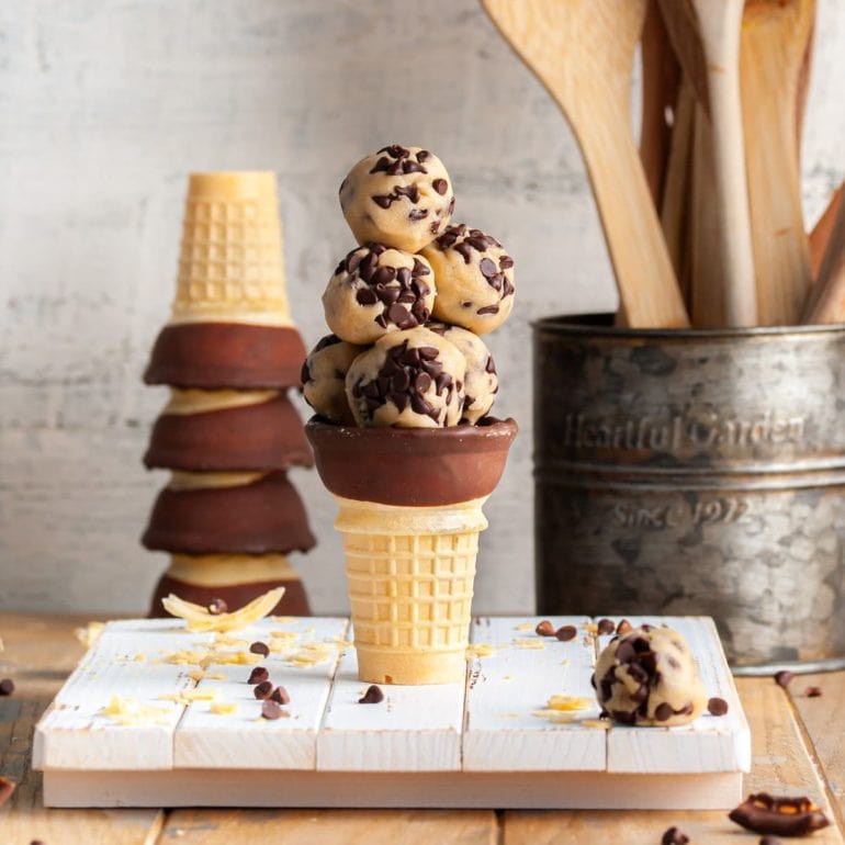 a stack of no-bake cookie dough bites in a chocolate dipped ice cream cone