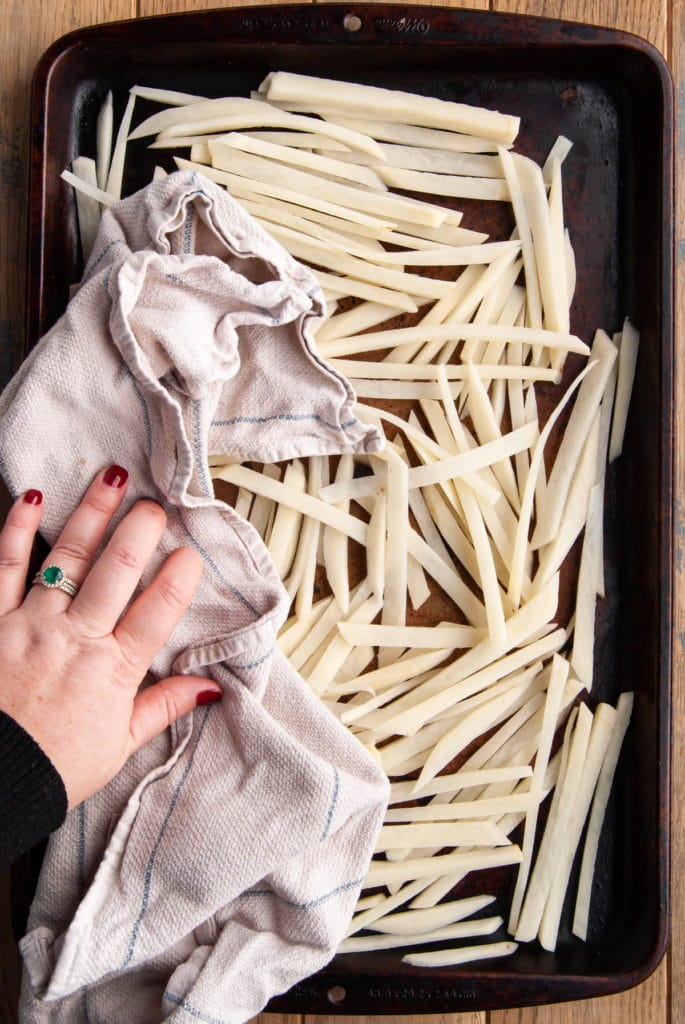 using a clean kitchen towel to dry  handcut fries