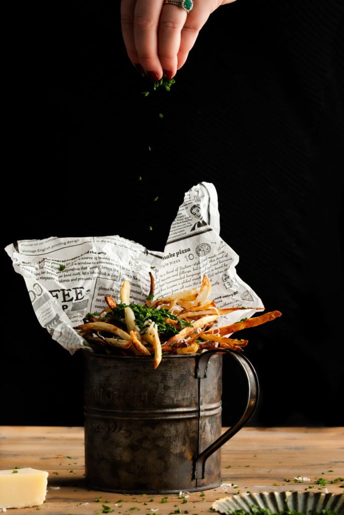 adding fresh parsley to parmesan truffle fries