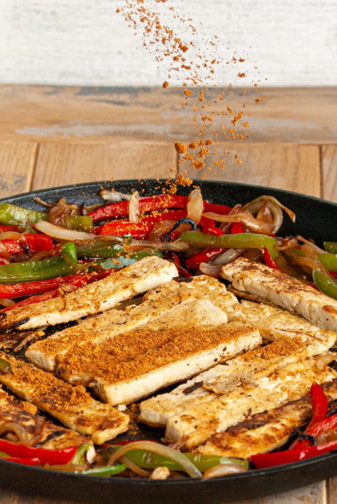 adding seasoning to tofu fajitas