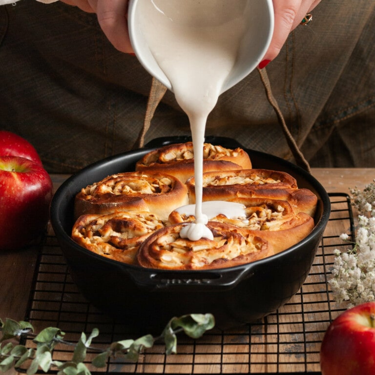 Pouring glaze over apple pie cinnamon rolls