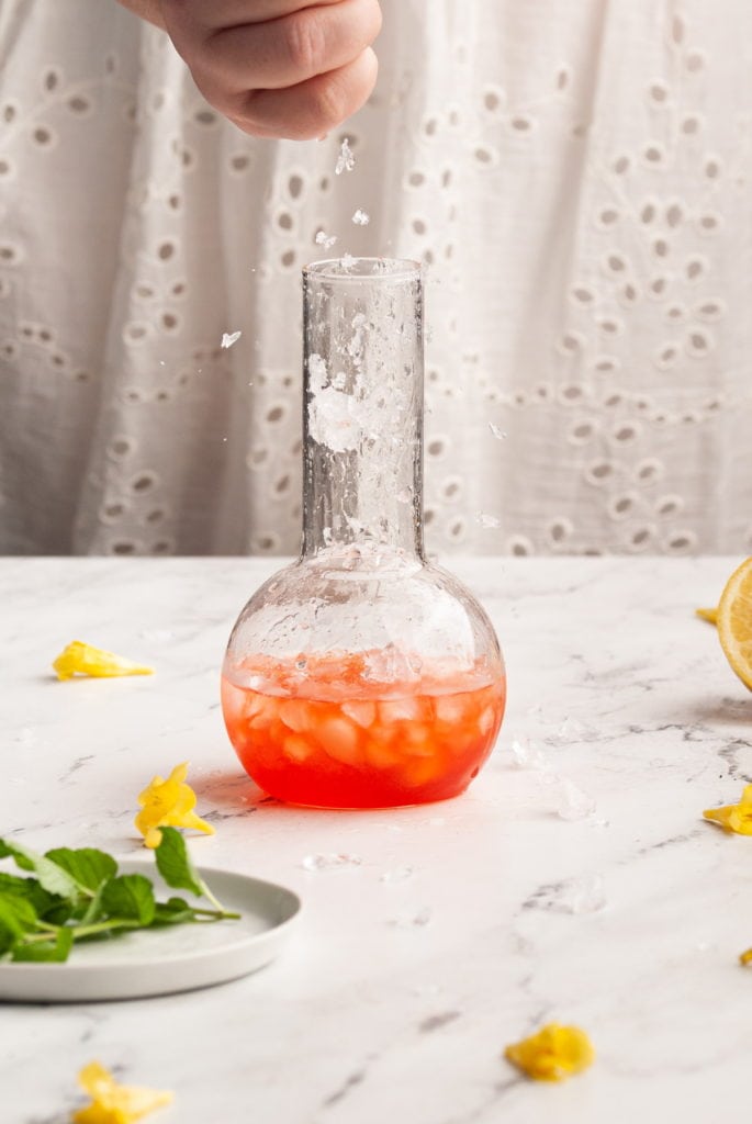 adding crushed ice to vibrant red cocktail