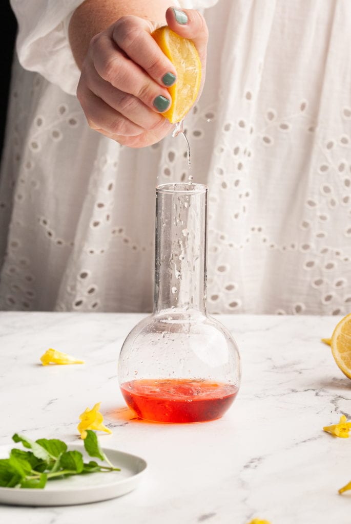 squeezing lemon juice into aperol bourbon cocktail