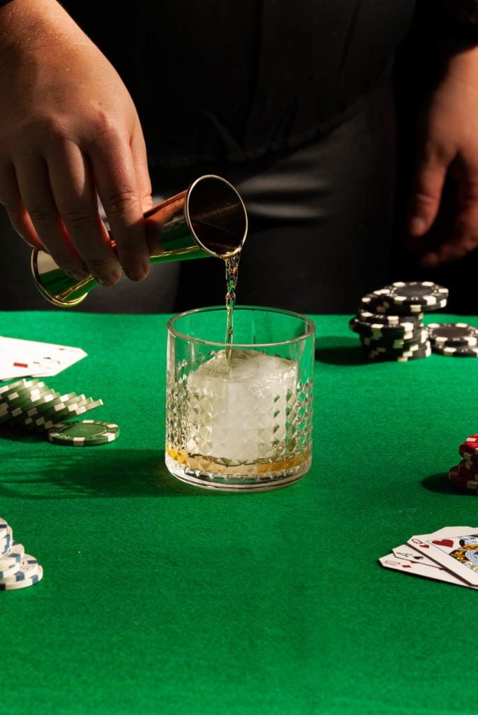 Pouring bourbon over whiskey ice in an old fashioned glass