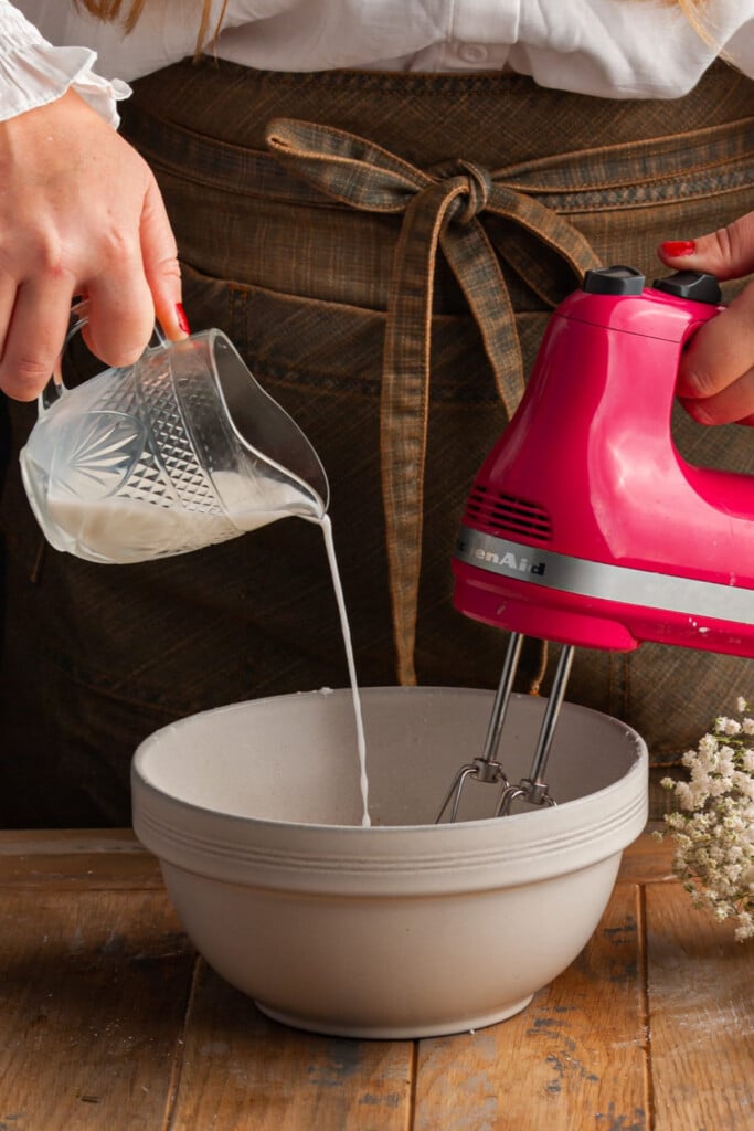 Adding milk with a hand mixer on to thin out icing.