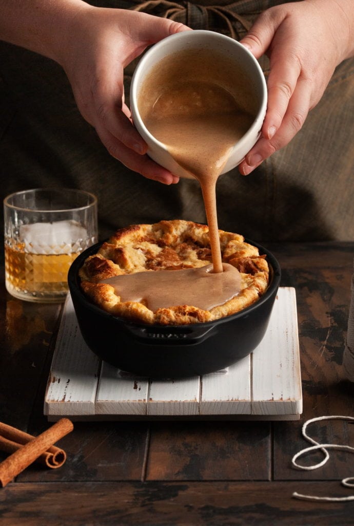 pouring bourbon sauce over bread pudding