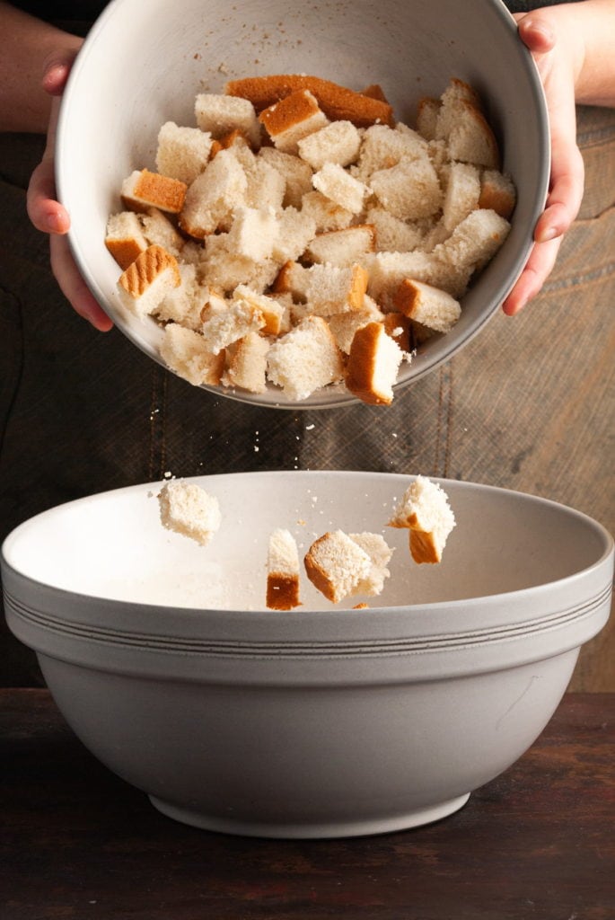 adding cubed bread to bread pudding