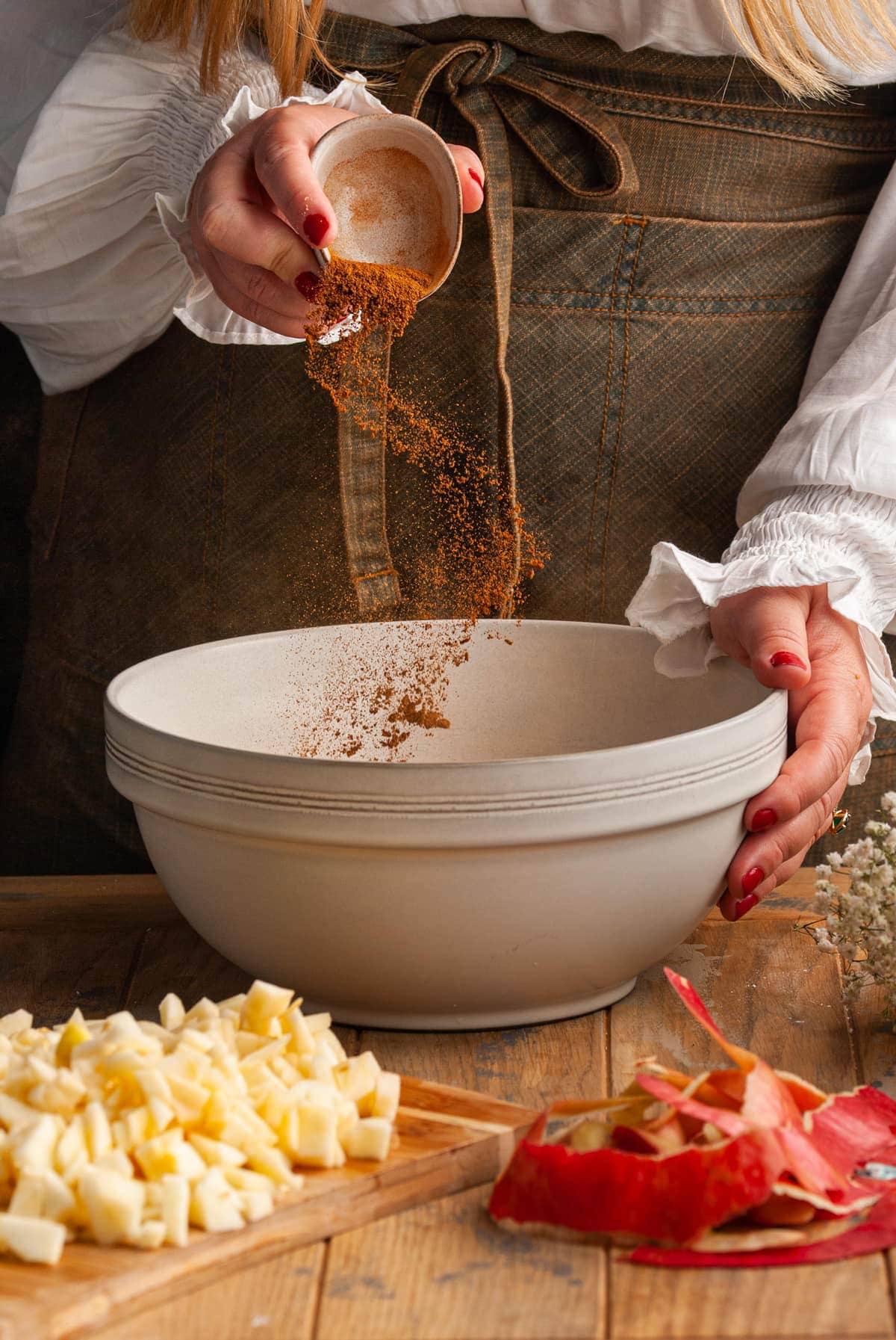 adding cinnamon to a large mixing bowl with butter and brown sugar