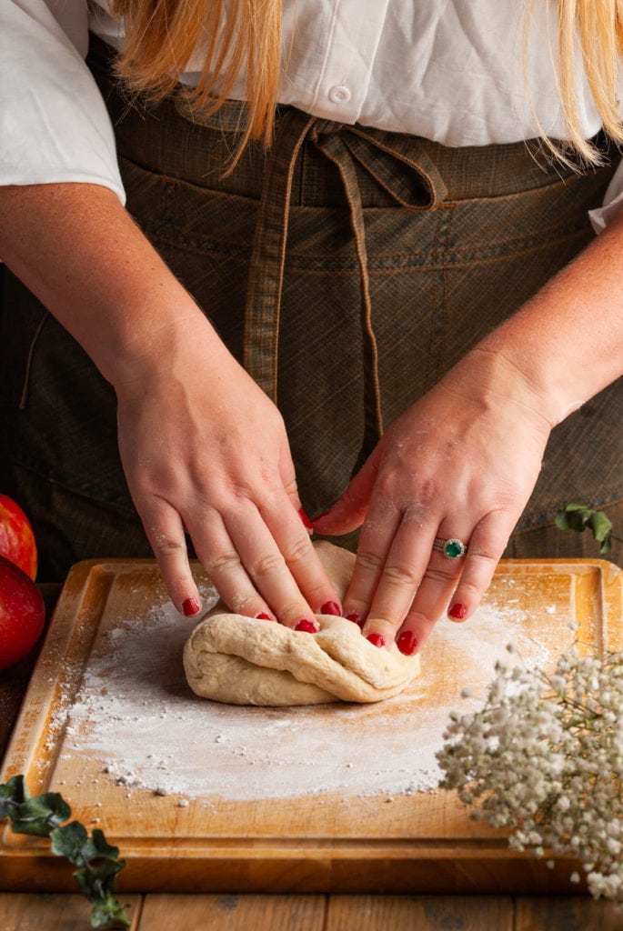 kneading cinnamon roll dough on a floured surface