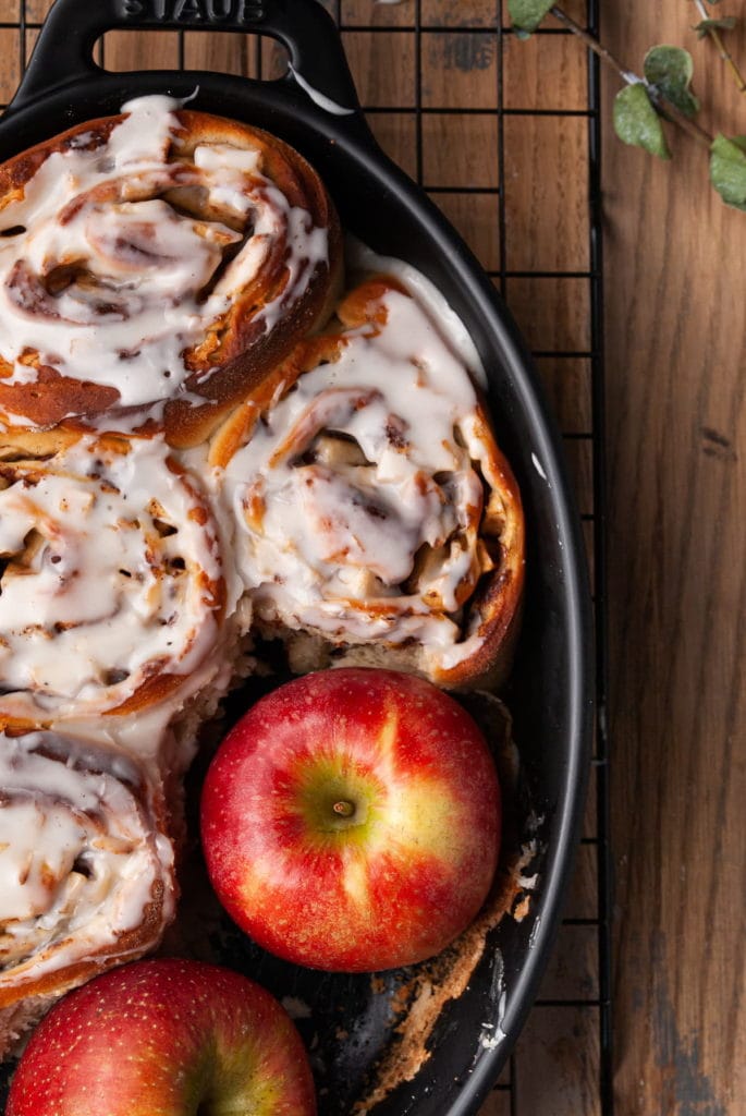baking dish with all cinnamon rolls and one red apple