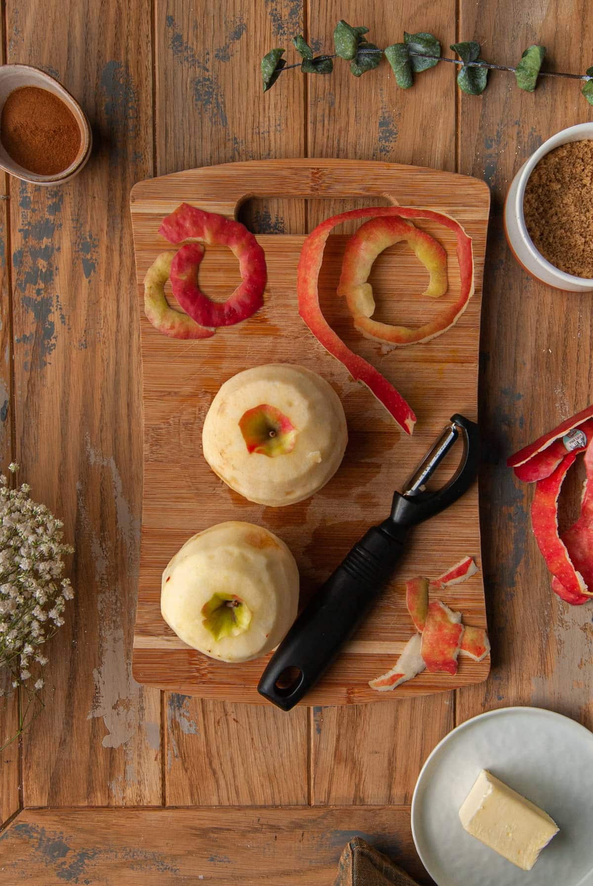 using a vegetable peeler to peel two apples