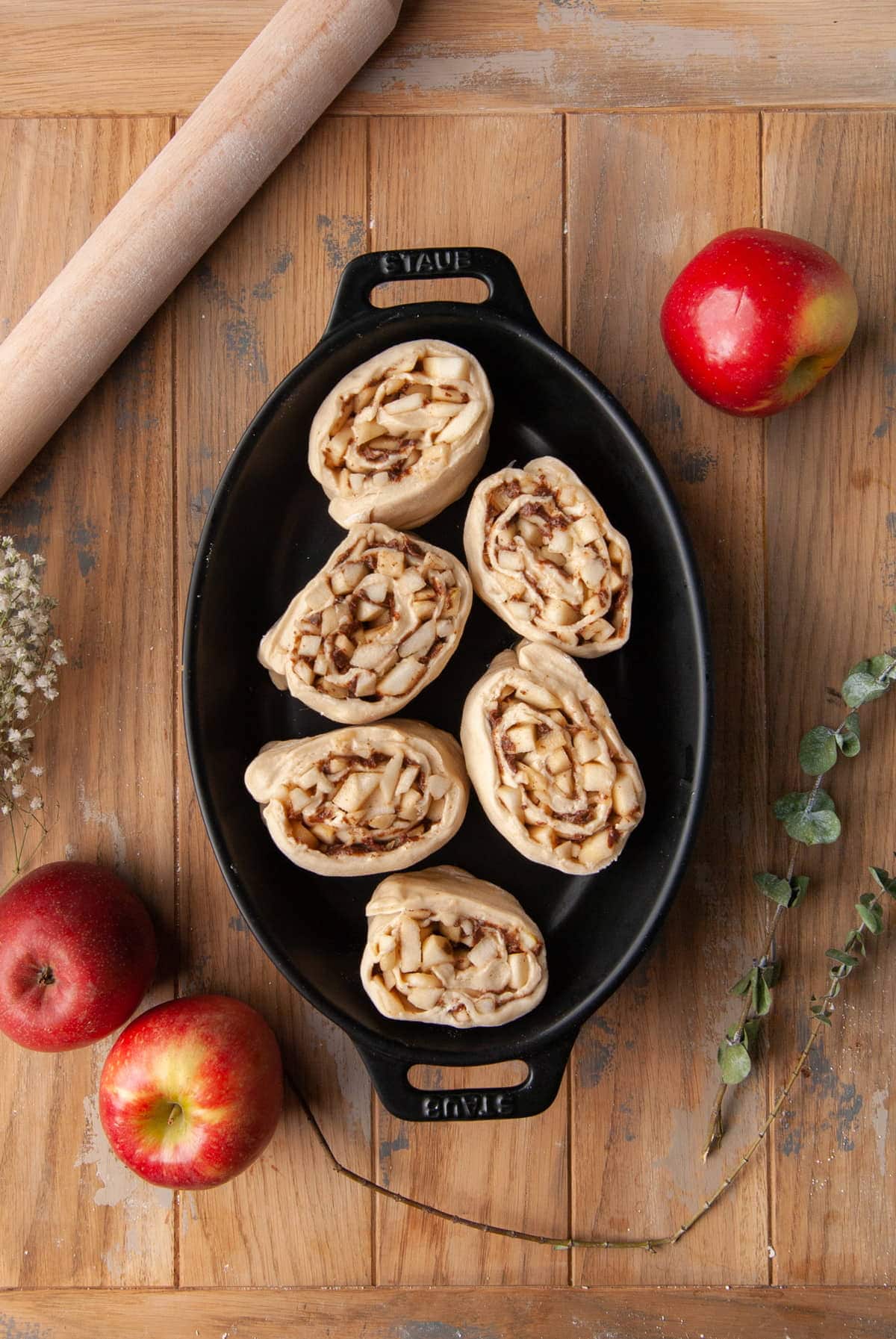 arranging cinnamon rolls in a baking dish to rise