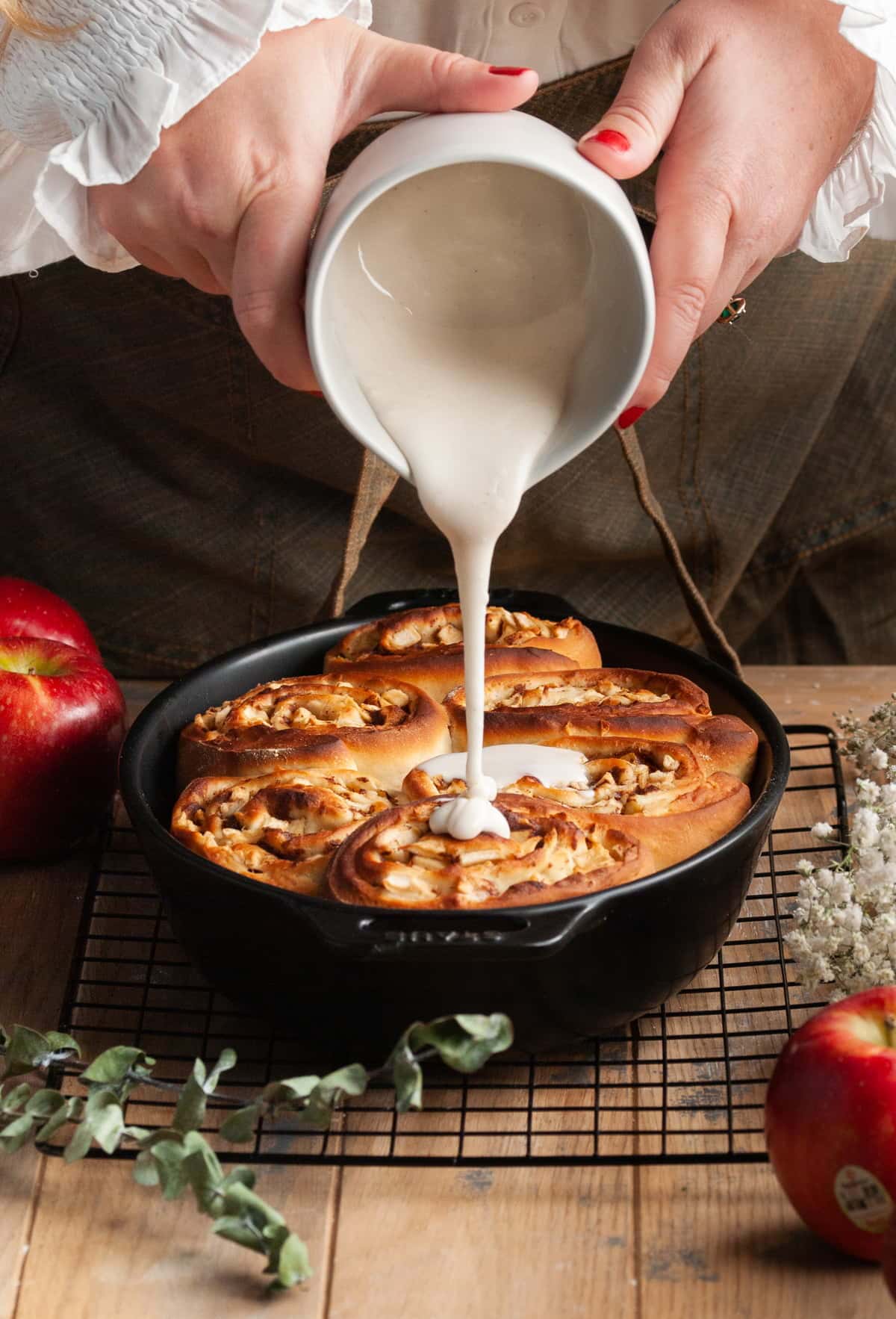 pouring icing over apple pie filled cinnamon rolls