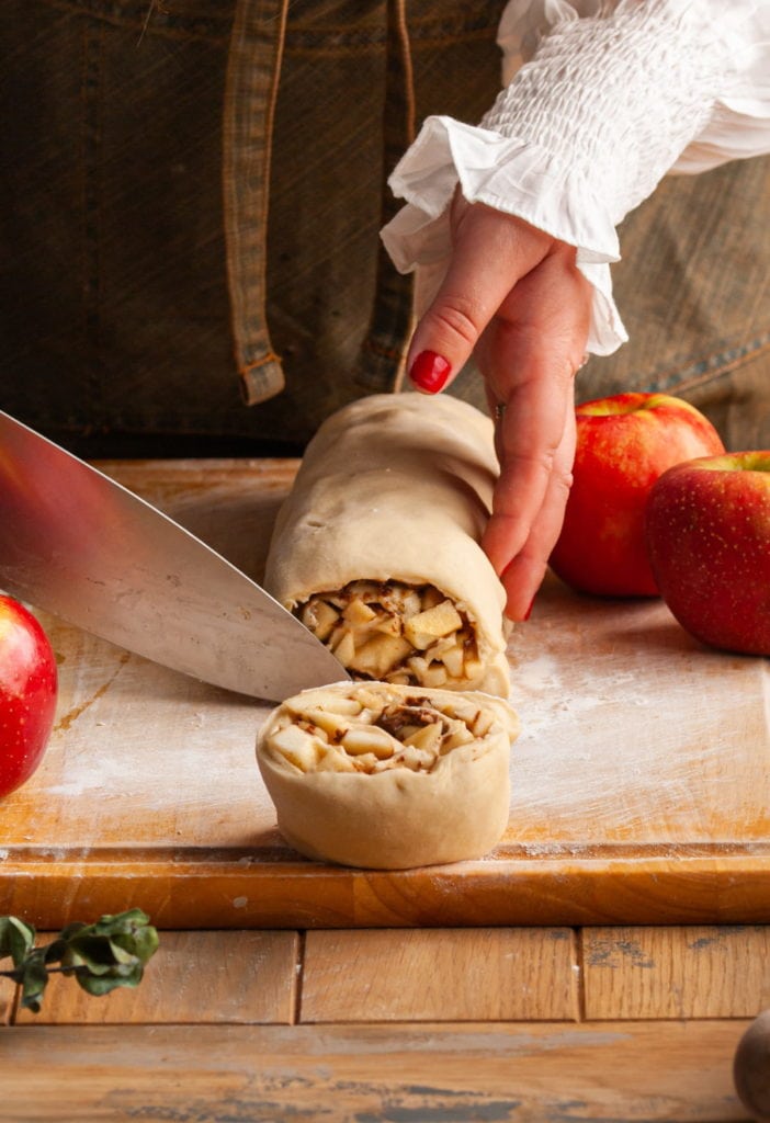 Slicing into rolled dough into individual cinnamon rolls