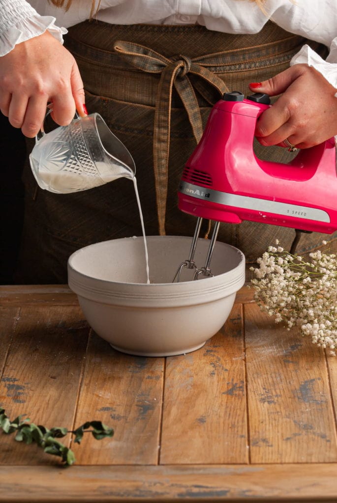 Using a hand mixer to whisk while adding milk to the icing