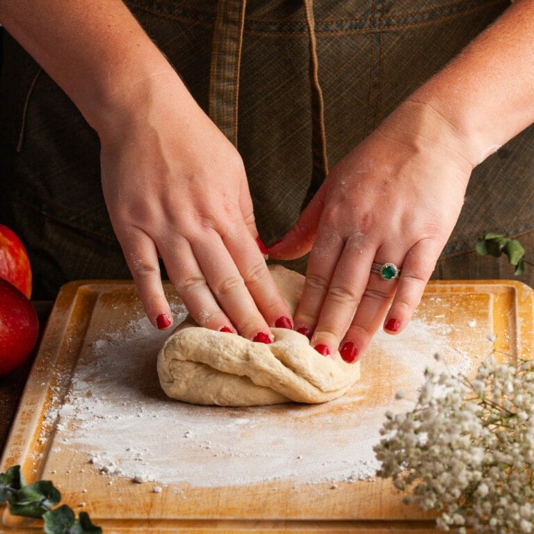 kneading cinnamon roll dough on a floured surface