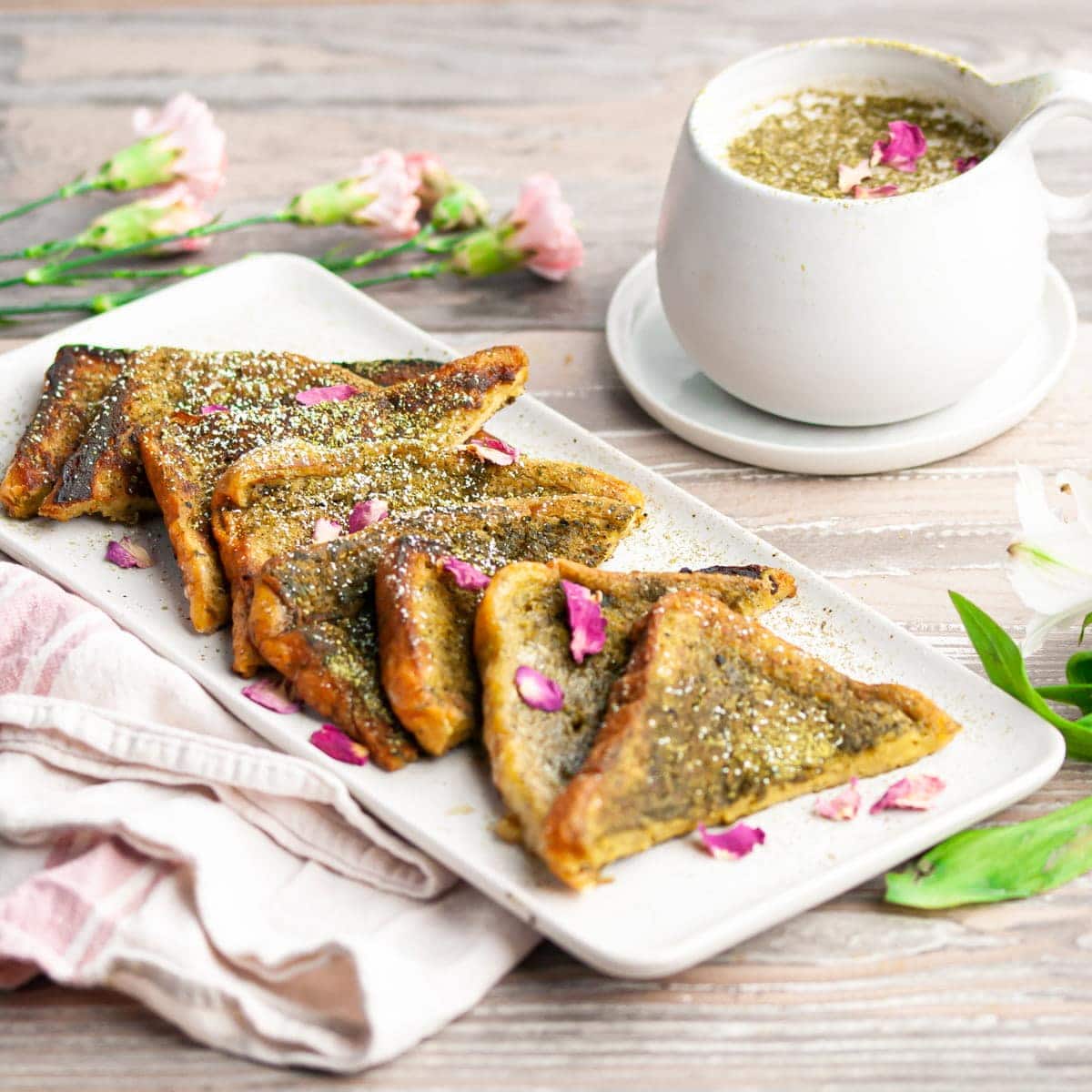 Platter of slices of matcha french toast garnished with edible rose petals