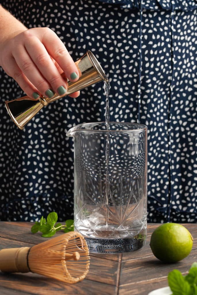 Adding rum to a mixing glass.