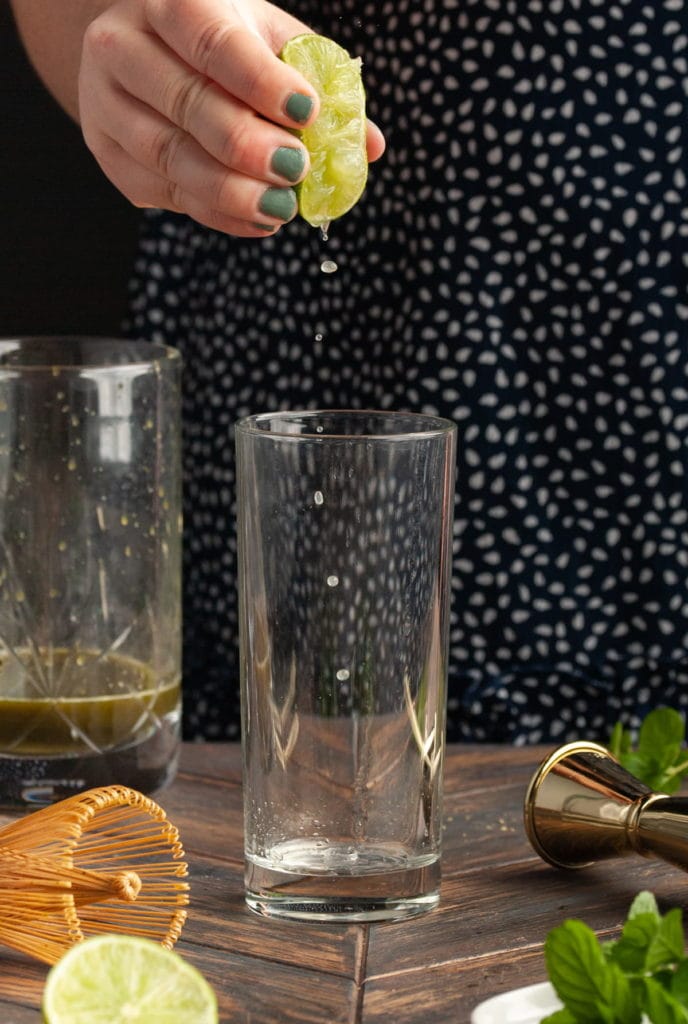 squeezing lime juice into a highball glass