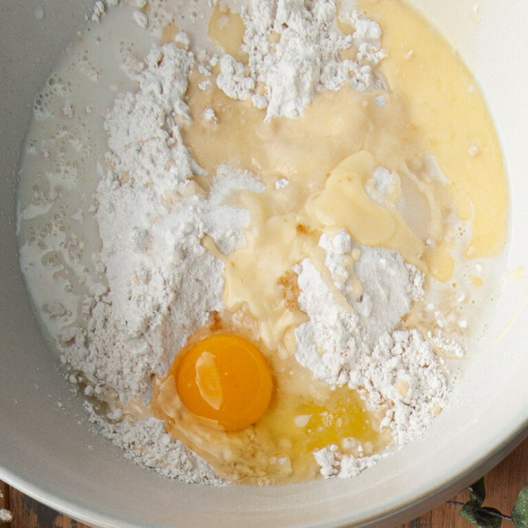 Adding cinnamon roll ingredients to a large mixing bowl