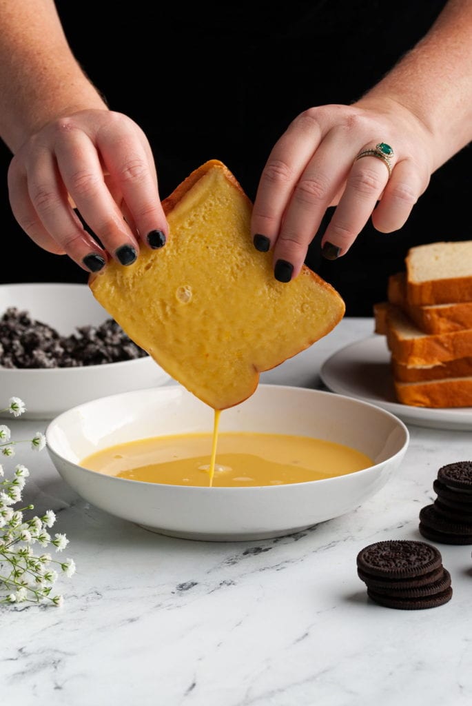 dipping slice of brioche bread into eggwash