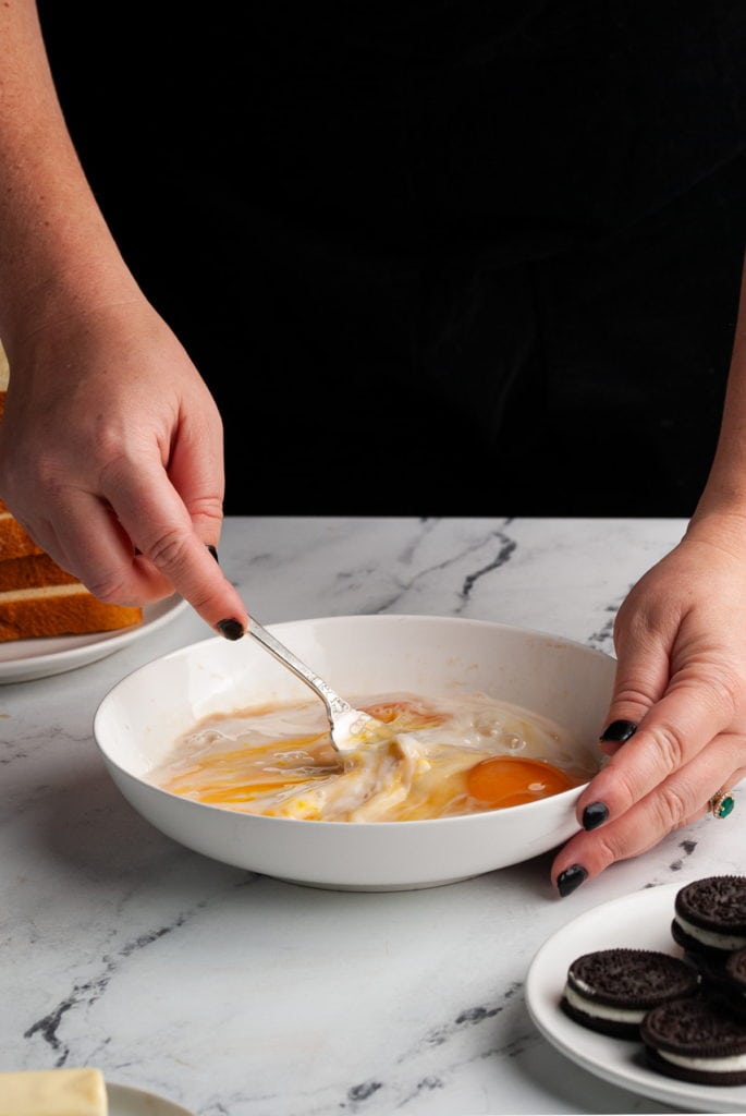 standing behind a bowl of egg wash whisking it together