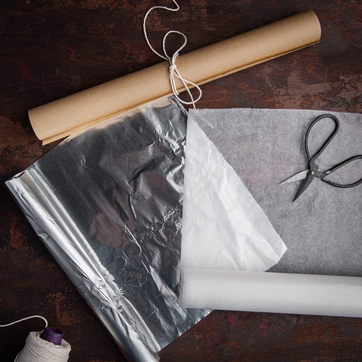 parchment paper, wax paper, and tin foil on a brown surface