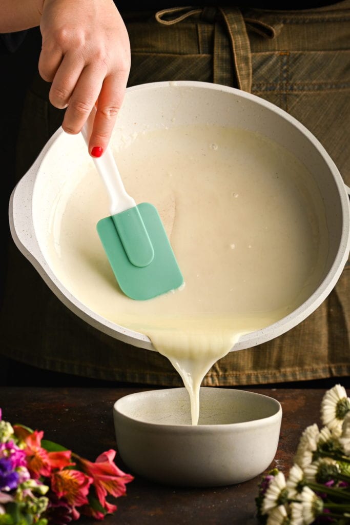 transferring brandy sauce for bread pudding into a bowl to cool